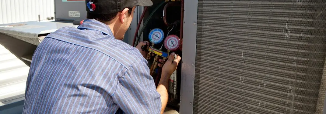 HVAC technician servicing a condenser unit in Phoenix